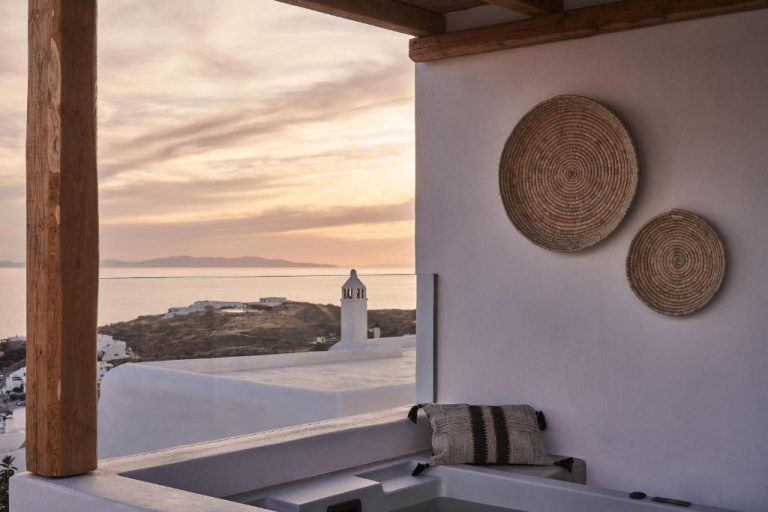 a balcony with a view of the ocean and a lighthouse at Amyth of Mykonos Agios Stefanos in Agios Stefanos 768x512