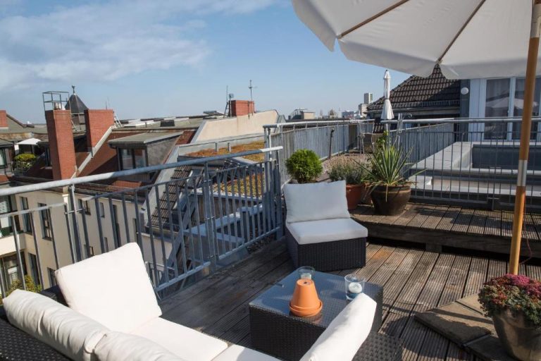 a balcony with chairs and an umbrella on a roof at Hotel Art Nouveau am Kurfurstendamm in Berlin 768x512