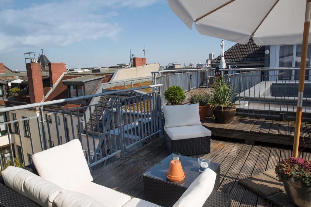 a balcony with chairs and an umbrella on a roof at Hotel Art Nouveau am Kurfurstendamm in Berlin