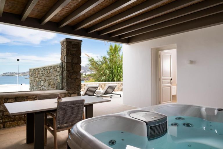 a bathroom with a tub and a table and chairs at Bonzoe Suites Villas in Mikonos 768x514