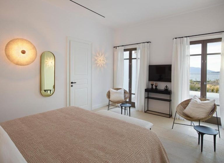 a bedroom with a bed and a desk and a television at Bonzoe Suites Villas in Mikonos 768x560