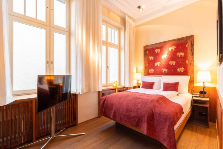 a bedroom with a bed and a flat screen tv at Orania.Berlin in Berlin 768x512