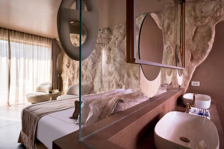 a bedroom with a bed and a sink and a mirror at Ethereum Luxury Suites a member of Mykonos Highlights in Mikonos 768x512