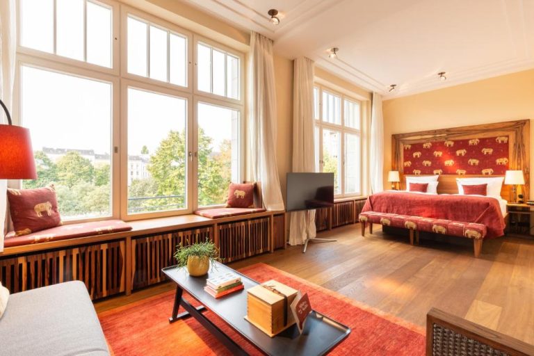 a bedroom with a bed and a tv and windows at Orania.Berlin in Berlin 768x512