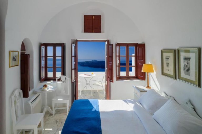 a bedroom with a bed and a view of the ocean at Aigialos Luxury Traditional Settlement in Fira 768x512