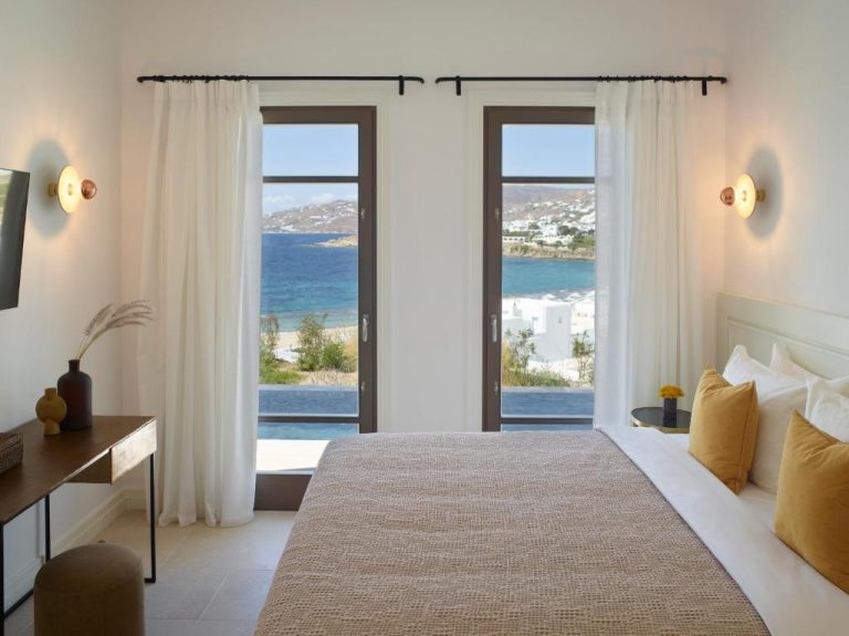a bedroom with a bed and a view of the ocean at Bonzoe Suites Villas in Mikonos 768x575