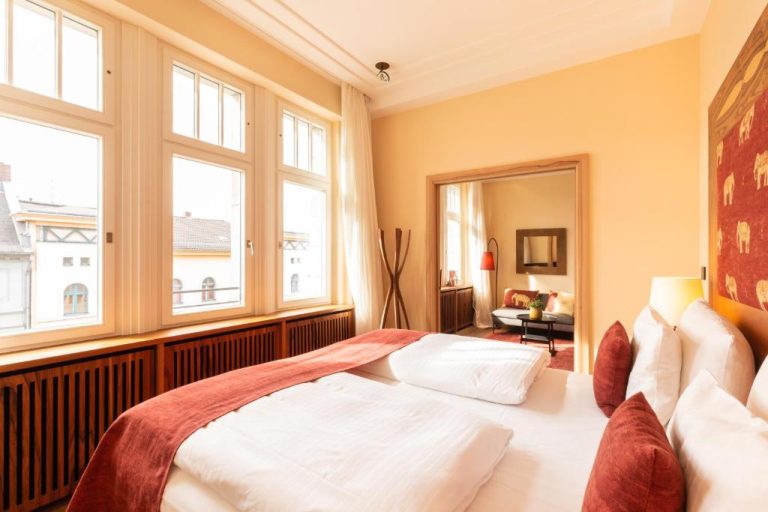 a bedroom with a bed in a room with windows at Orania.Berlin in Berlin 768x512