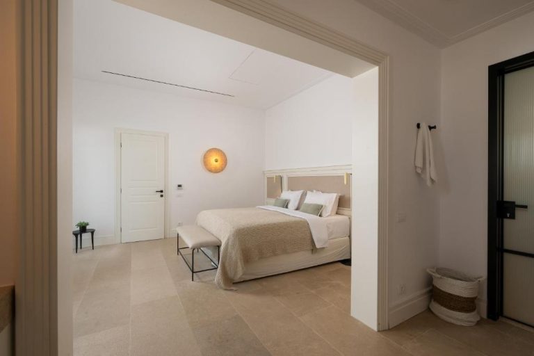 a bedroom with a bed in a white room at Bonzoe Suites Villas in Mikonos 768x512