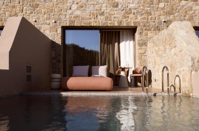 a bedroom with a bed next to a swimming pool at Ethereum Luxury Suites a member of Mykonos Highlights in Mikonos 768x504