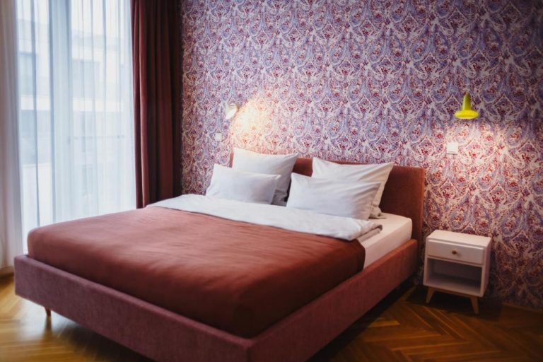 a bedroom with a bed with a red wall at The Circus Apartments in Berlin 768x512
