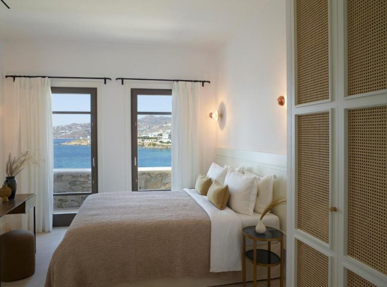 a bedroom with a bed with a view of the ocean at Bonzoe Suites Villas in Mikonos 1 768x569