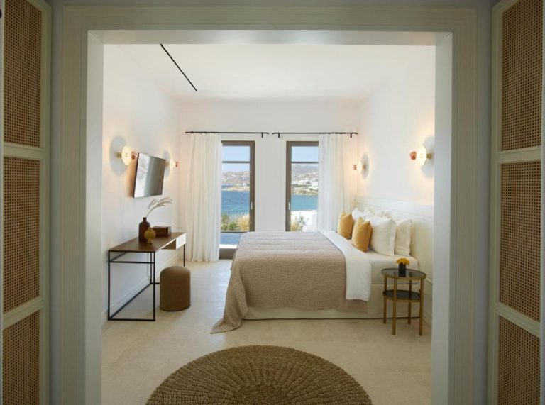 a bedroom with a bed with a view of the ocean at Bonzoe Suites Villas in Mikonos 768x571