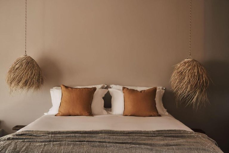 a bedroom with a bed with brown and white pillows at Amyth of Mykonos Agios Stefanos in Agios Stefanos 768x512
