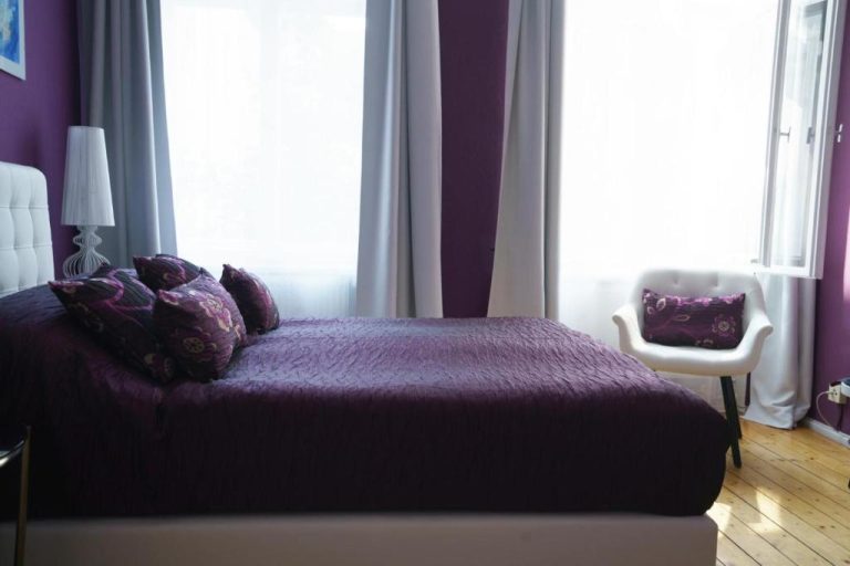 a bedroom with a bed with purple sheets and a window at Boutique Hotel Mittendrin Berlin in Berlin 768x512