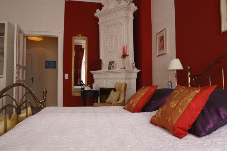 a bedroom with a bed with red walls and a fireplace at Boutique Hotel Mittendrin Berlin in Berlin 768x512