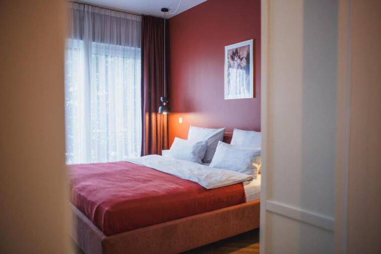 a bedroom with a bed with red walls and a window at The Circus Apartments in Berlin 768x512