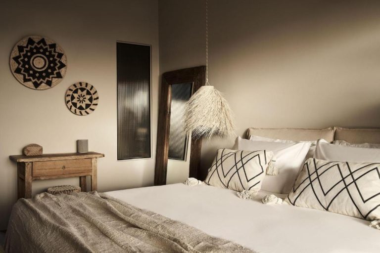 a bedroom with a bed with white sheets and pillows at Amyth of Mykonos Agios Stefanos in Agios Stefanos 1 768x512