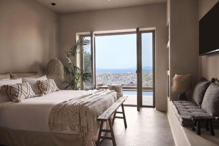 a bedroom with a large bed and a large window at Amyth of Mykonos Agios Stefanos in Agios Stefanos 768x512