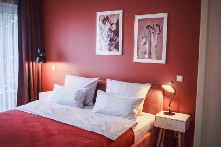 a bedroom with red walls and a bed with white pillows at The Circus Apartments in Berlin 768x512