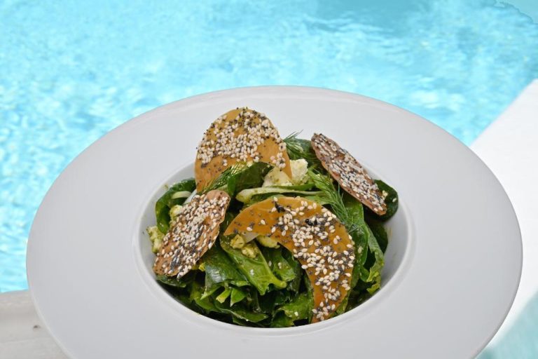 a bowl of salad with sesame seeds on a plate at Aigialos Luxury Traditional Settlement in Fira 768x512