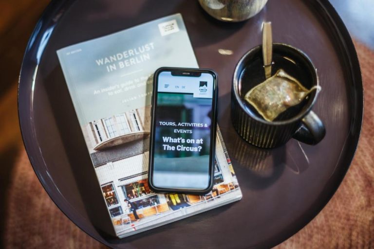a cell phone on a table with a book and a cup of coffee at The Circus Apartments in Berlin 768x512