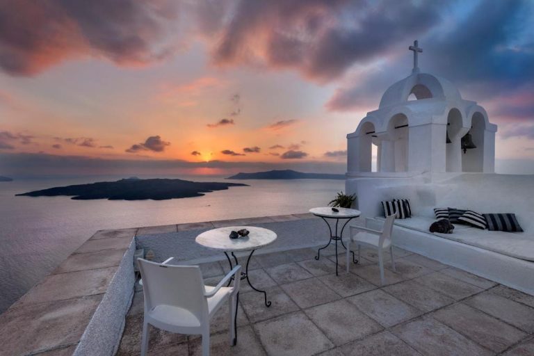 a church with chairs and a table and a sunset at Aigialos Luxury Traditional Settlement in Fira 768x512