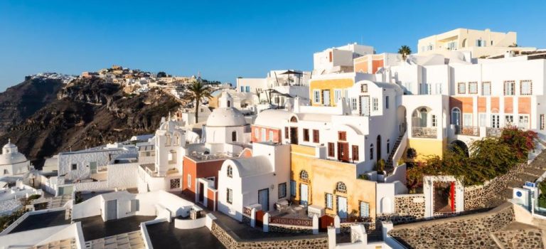 a cluster of white houses on the side of a mountain at Aigialos Luxury Traditional Settlement in Fira 768x350