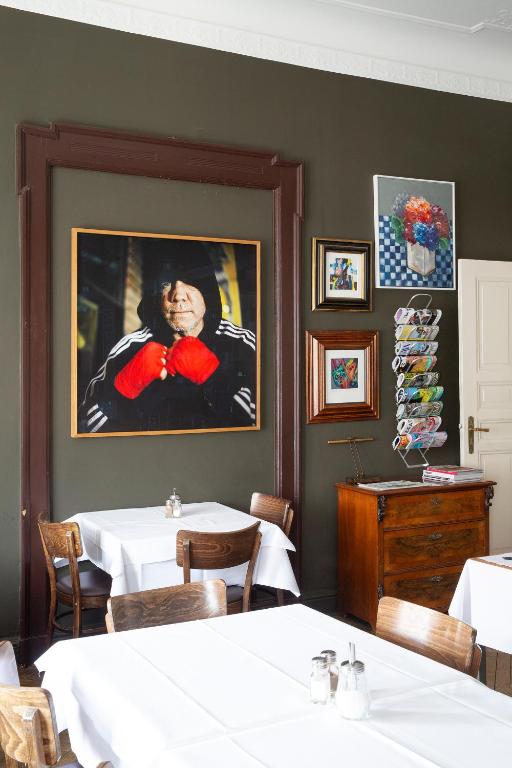 a dining room with tables and a painting of a man at Hotel Art Nouveau am Kurfurstendamm in Berlin
