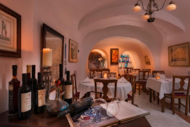 a dining room with wine bottles on a table at Aigialos Luxury Traditional Settlement in Fira 768x512