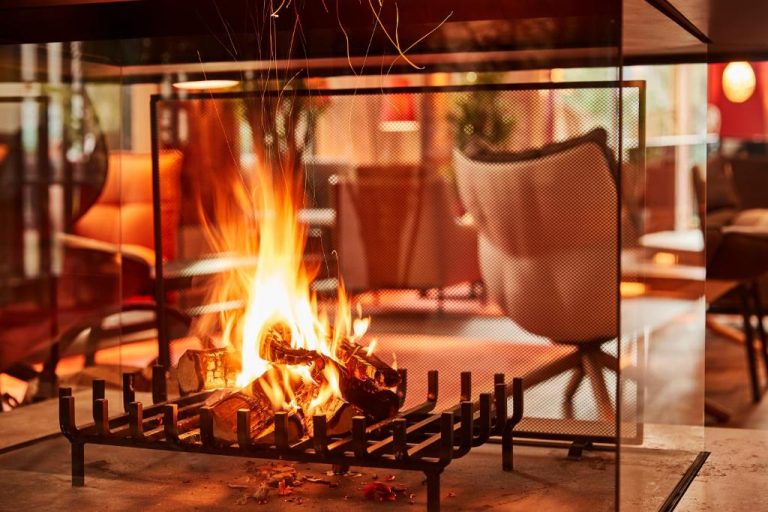 a fire in a fireplace in a room with a chair at Orania.Berlin in Berlin 768x512