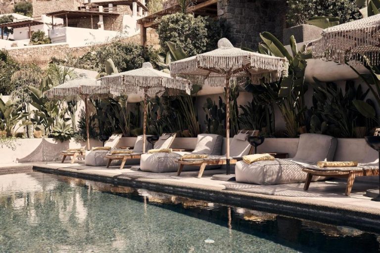 a group of chairs and umbrellas next to a pool at Amyth of Mykonos Agios Stefanos in Agios Stefanos 768x512