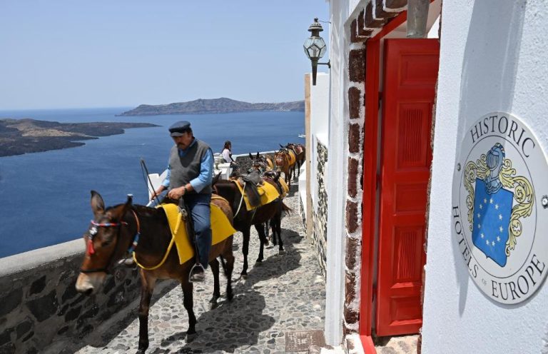 a group of people riding horses down a building at Aigialos Luxury Traditional Settlement in Fira 768x496