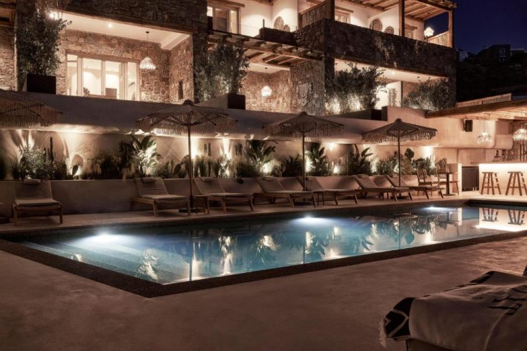 a hotel pool with chairs and umbrellas at night at Amyth of Mykonos Agios Stefanos in Agios Stefanos 768x512