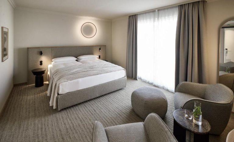 a hotel room with a large bed and chairs at ADELANTE Boutique Hotel in Berlin 768x467