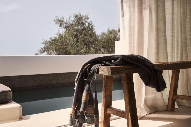 a jacket sitting on top of a wooden chair at Amyth of Mykonos Agios Stefanos in Agios Stefanos 768x512