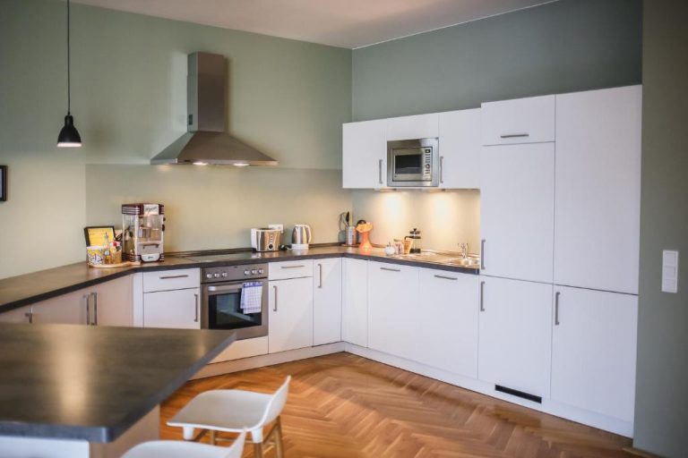 a kitchen with white cabinets and a wooden floor at The Circus Apartments in Berlin 768x512
