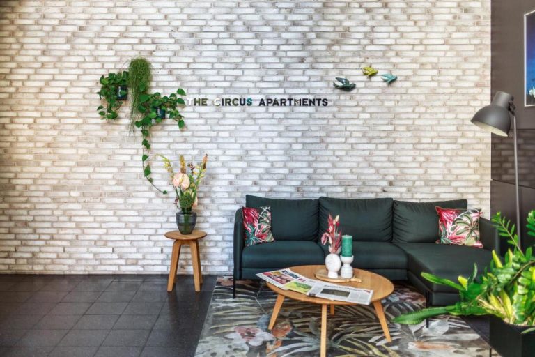a living room with a couch and a brick wall at The Circus Apartments in Berlin 768x512