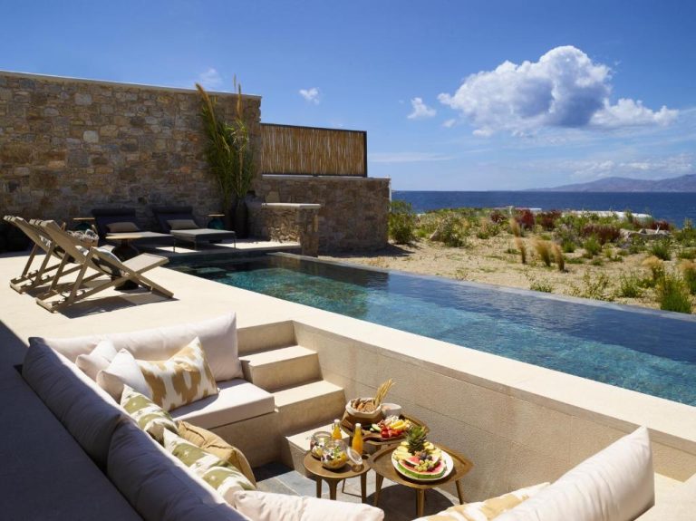 a living room with a couch and a swimming pool at Bonzoe Suites Villas in Mikonos 768x575