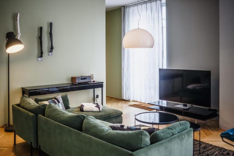 a living room with a green couch and a television at The Circus Apartments in Berlin 768x512