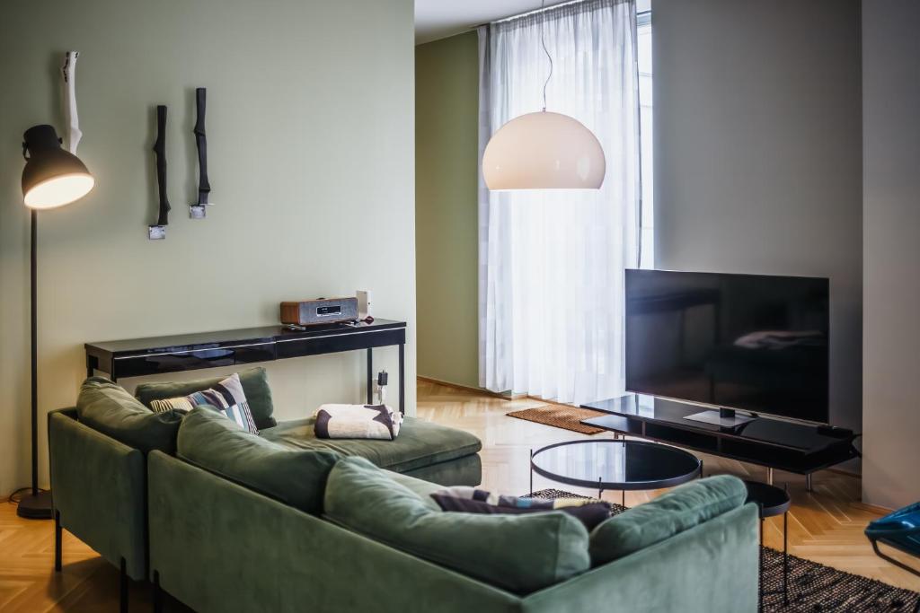 a living room with a green couch and a television at The Circus Apartments in Berlin
