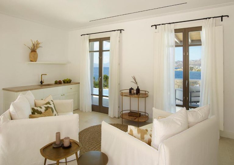 a living room with white furniture and a view of the ocean at Bonzoe Suites Villas in Mikonos 768x540