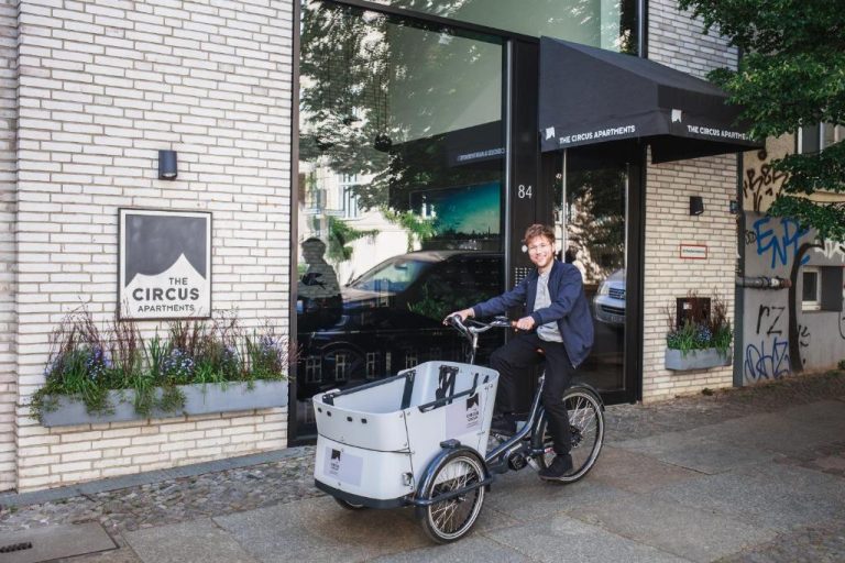 a man riding a bike with a cooler on the back at The Circus Apartments in Berlin 768x512