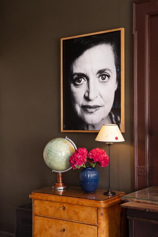 a picture of a woman on a wall above a table with flowers at Hotel Art Nouveau am Kurfurstendamm in Berlin