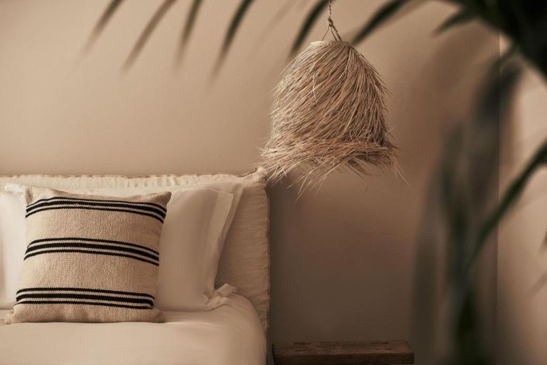 a pillow sitting on a couch next to a plant at Amyth of Mykonos Agios Stefanos in Agios Stefanos 768x512