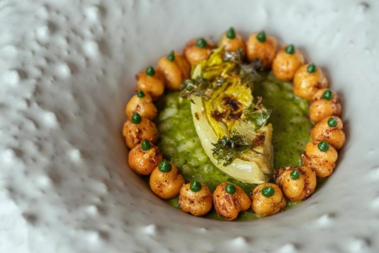 a plate of food with chickpeas and green sauce at BillCoo Mykonos The Leading Hotels of the World in Mikonos 768x512