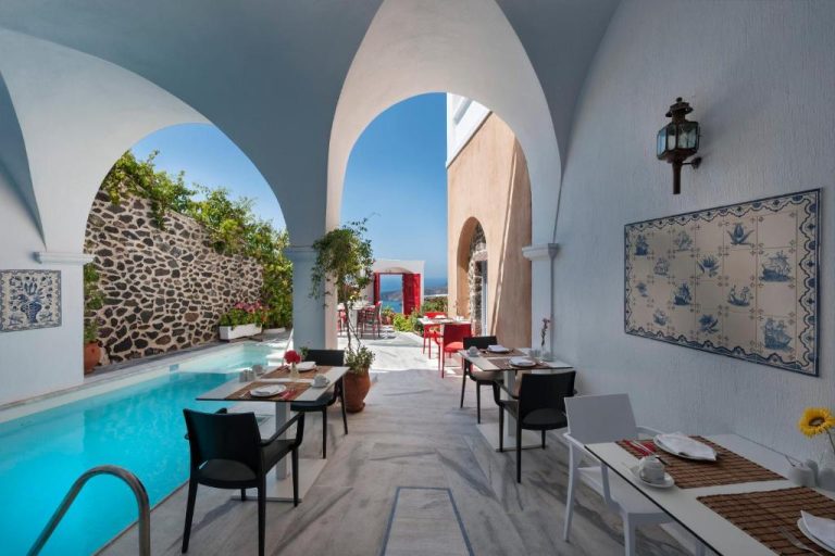 a restaurant with a swimming pool and tables and chairs at Aigialos Luxury Traditional Settlement in Fira 768x512