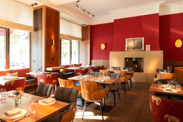 a restaurant with tables and chairs and a fireplace at Orania.Berlin in Berlin 768x512