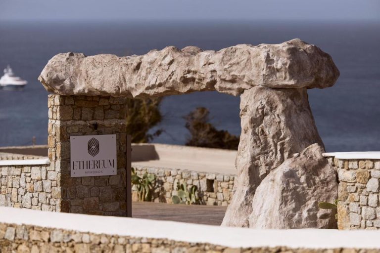 a stone wall with a sign in front of the ocean at Ethereum Luxury Suites a member of Mykonos Highlights in Mikonos 768x512