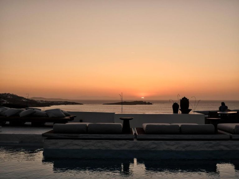 a sunset over a body of water with couches at Boheme Mykonos Town Small Luxury Hotels of the World in Mikonos 768x576