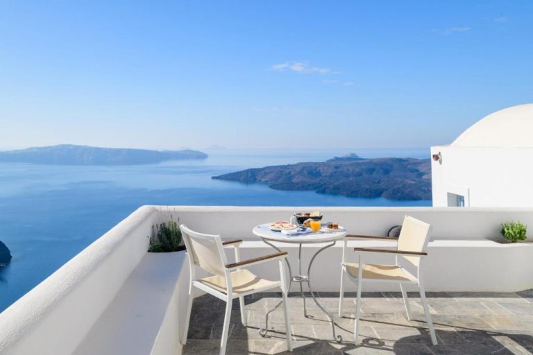 a table and chairs on a balcony overlooking the ocean at Aigialos Luxury Traditional Settlement in Fira 768x512